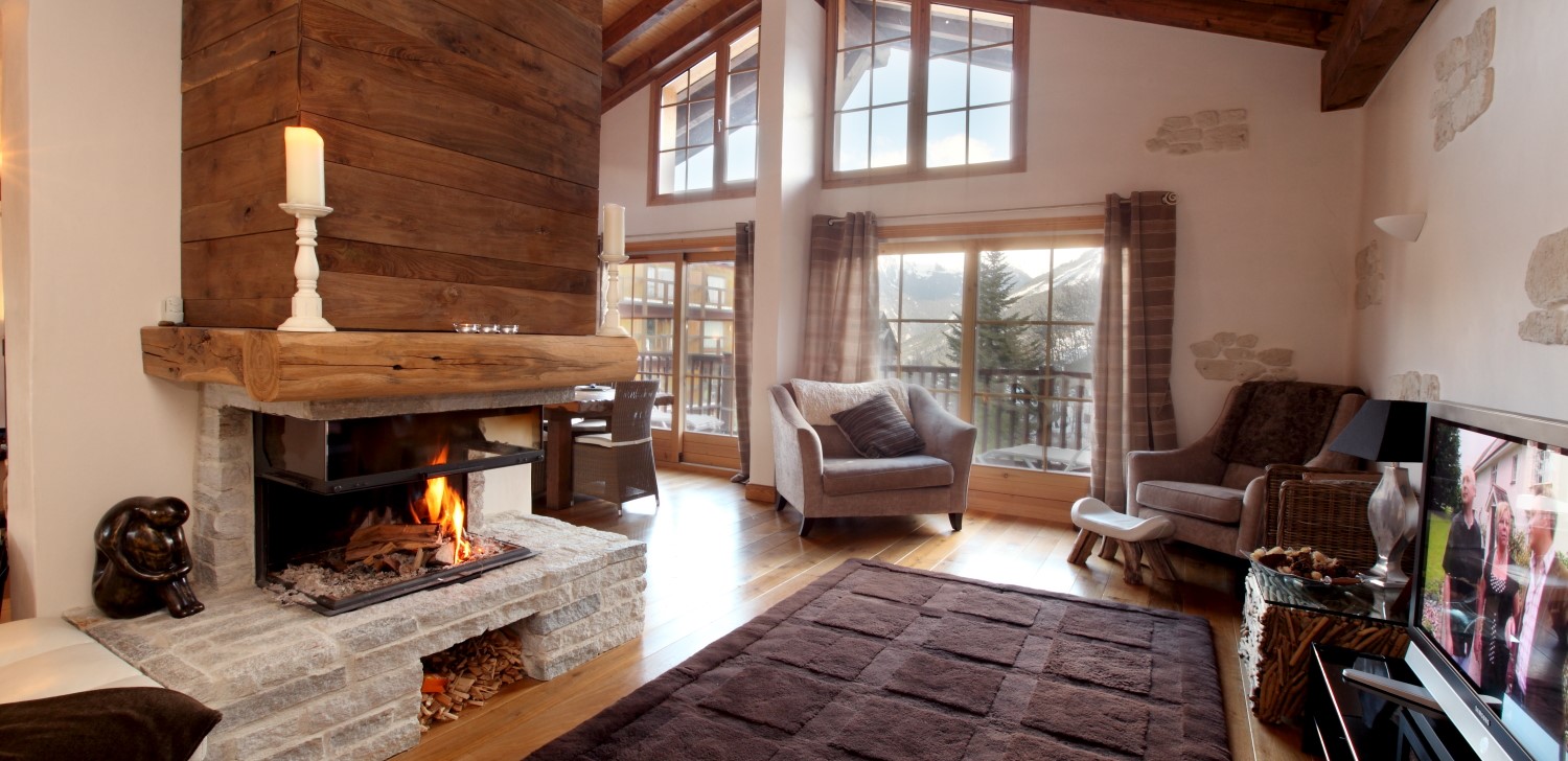 Chalet lounge with open fireplace and armchairs